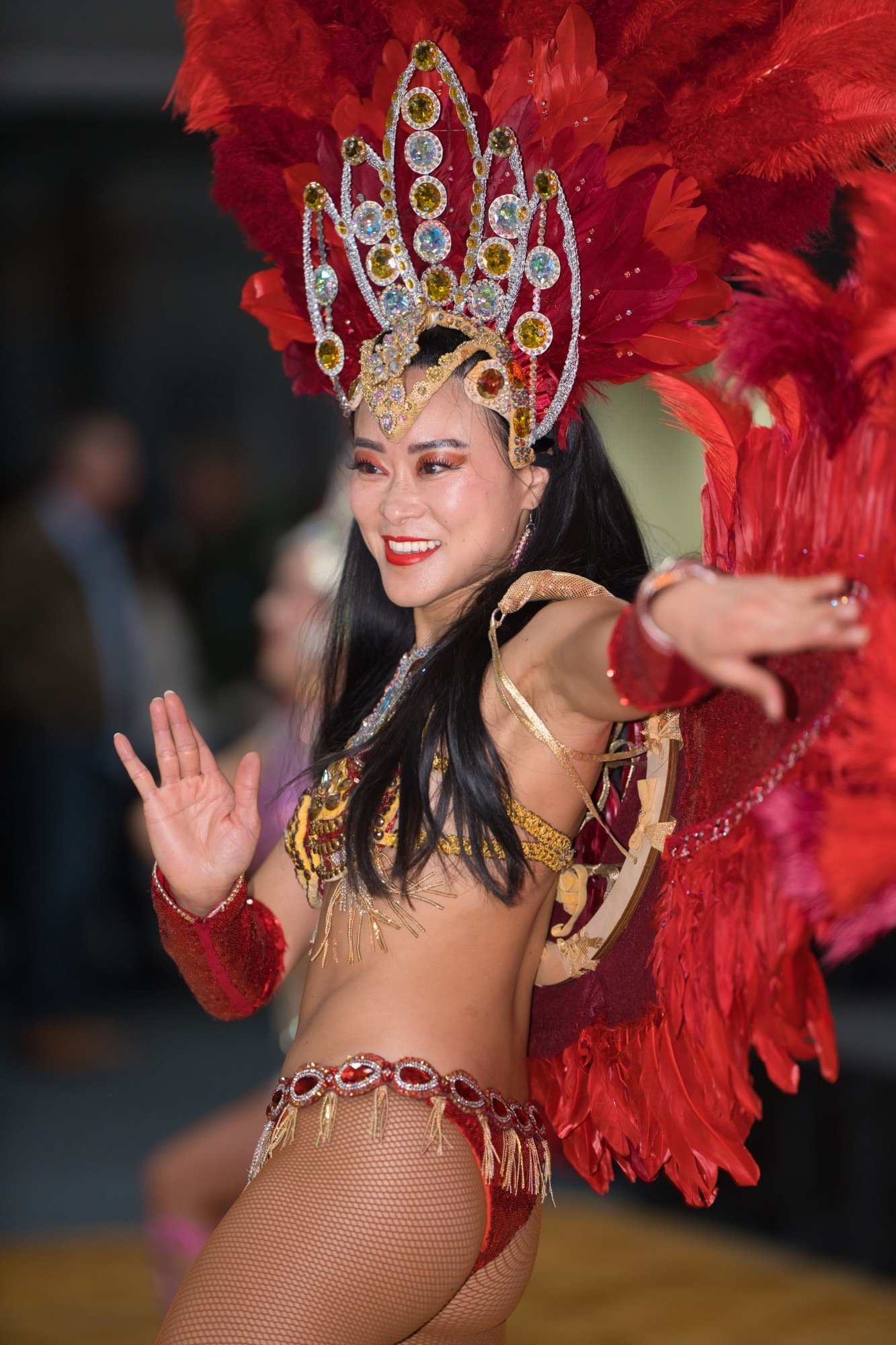 Samba dancers in red feathered carnival costumes with a drummer behind them